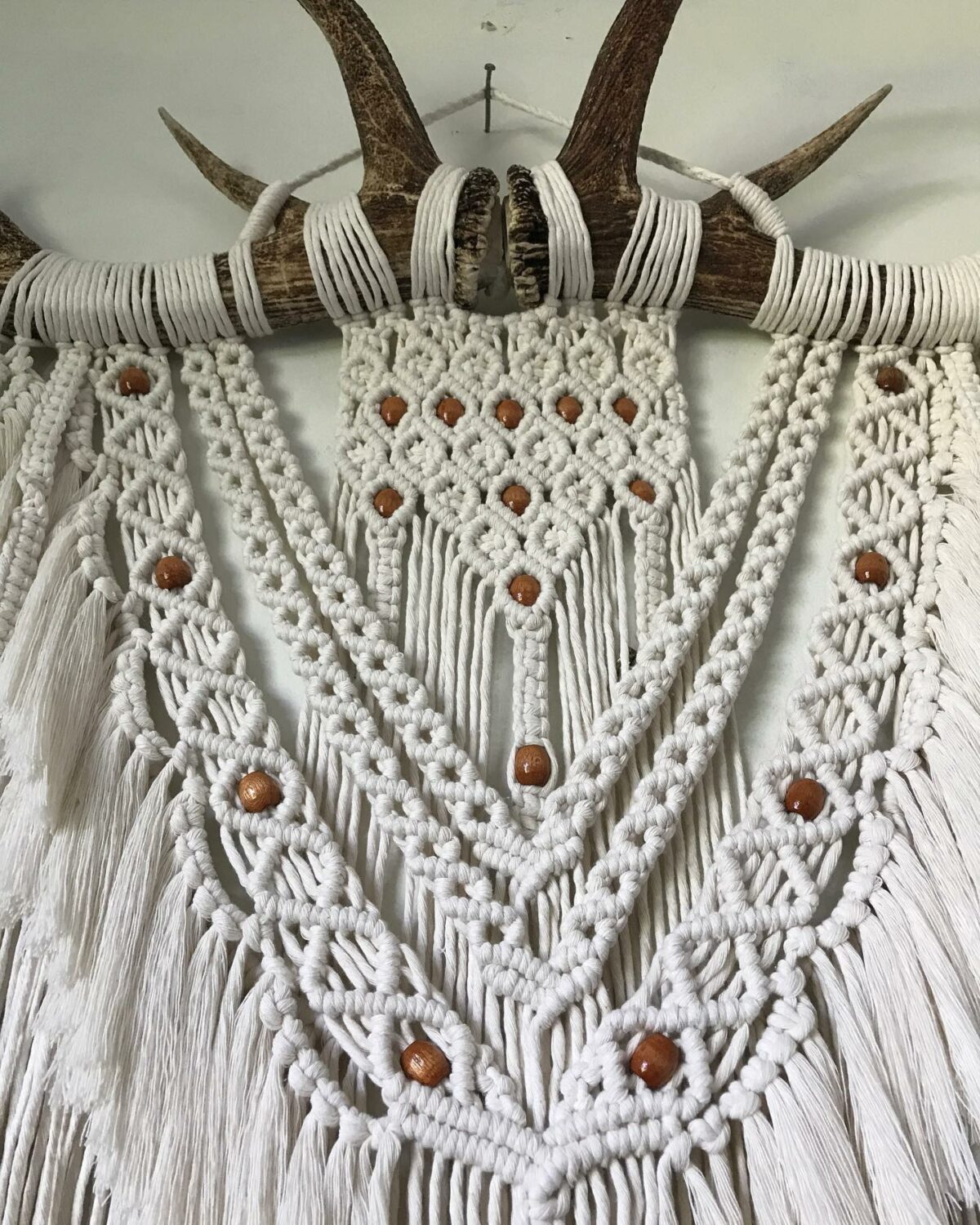 Macrame artwork on antlers with beading details