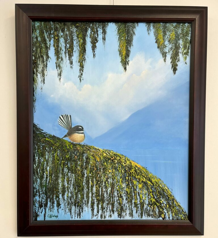 Framed painting titled "Piwakawaka Fantail" featuring a bird perched on a moss-covered branch with overhanging foliage, set against a blue sky and mountain backdrop.