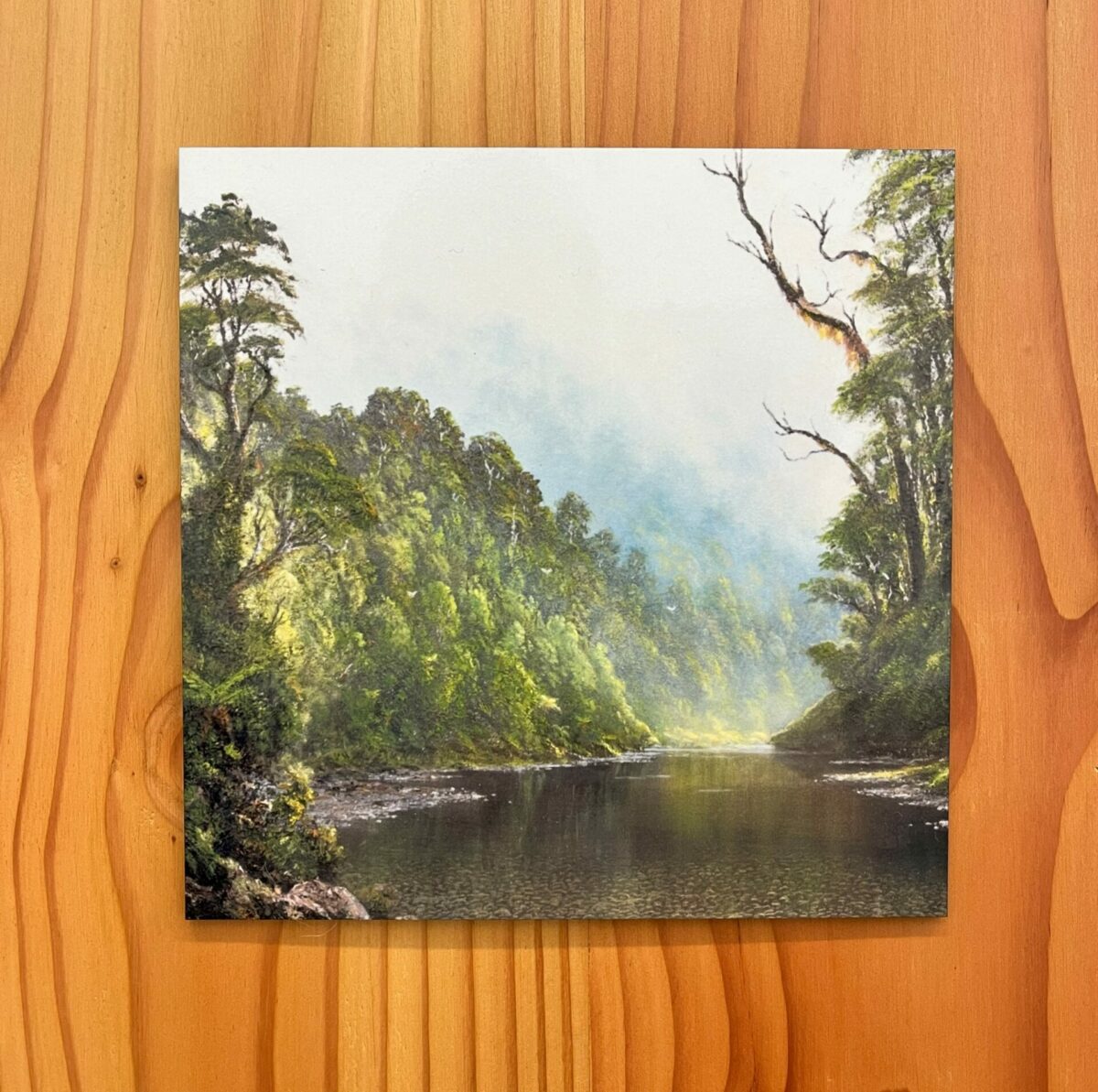 A depiction of a serene river winding through a forest, enveloped in lush greenery and gentle sunlight, set against the Browns Creek Buller Wall Tile.