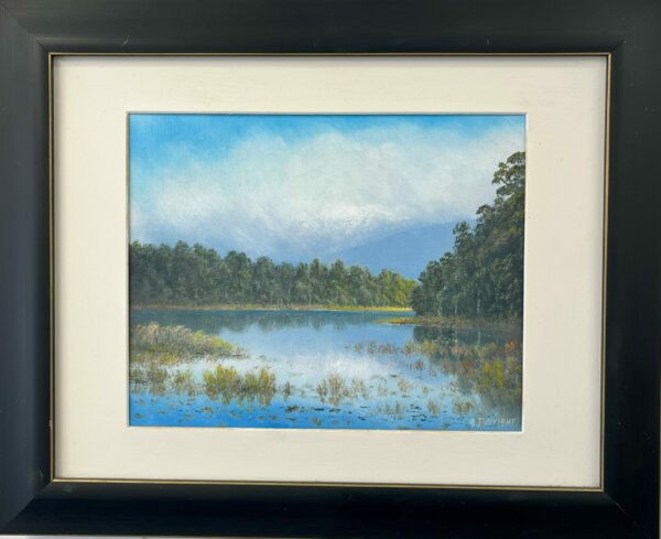 Framed landscape painting titled "Lake Mahinipua," depicting a lake encircled by trees beneath a clear blue sky.