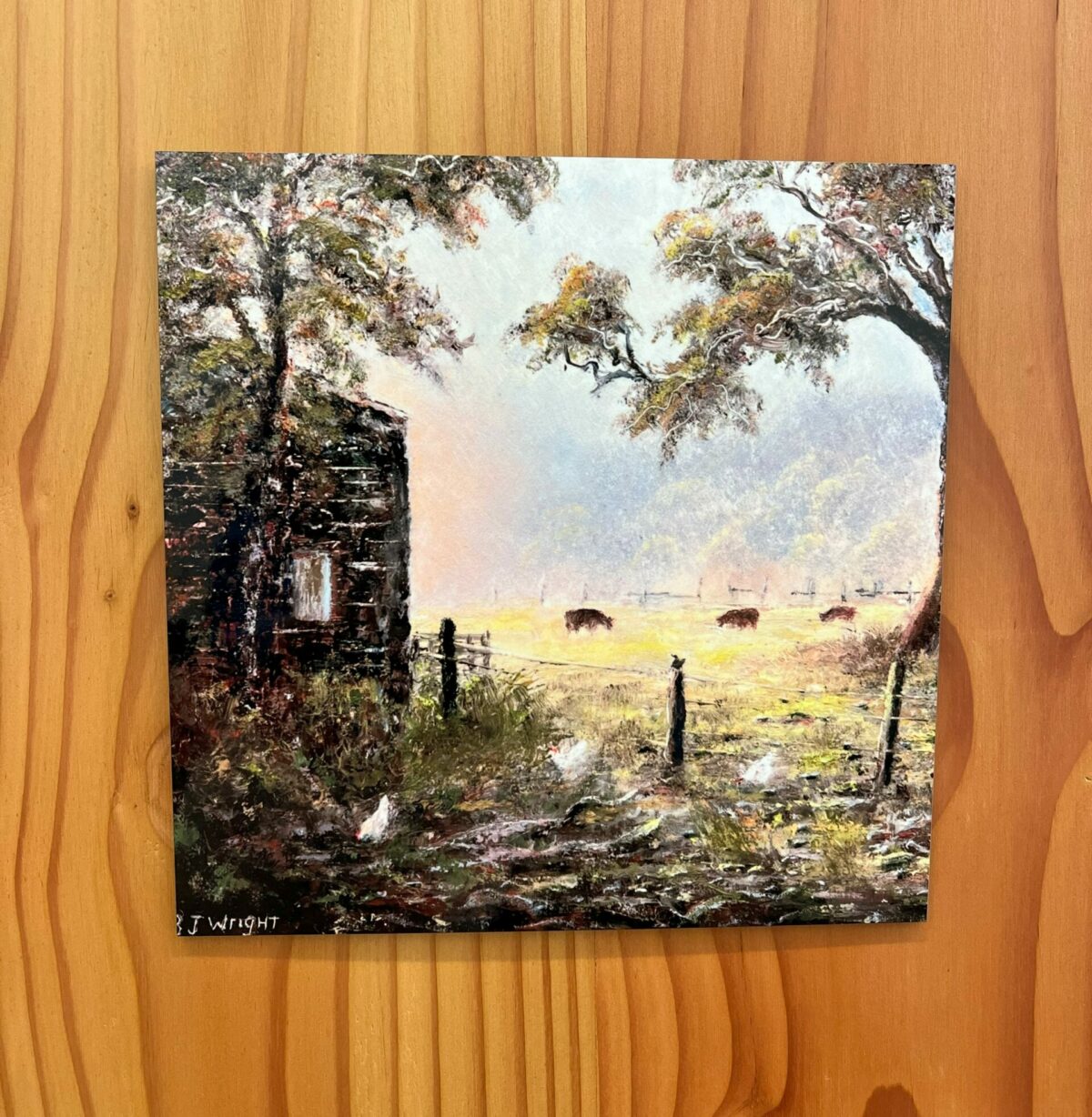 The Morning Light wall tile beautifully captures a serene rural scene featuring cows grazing in a sunlit field, chickens near a wooden shed, and trees adorned with autumn foliage.